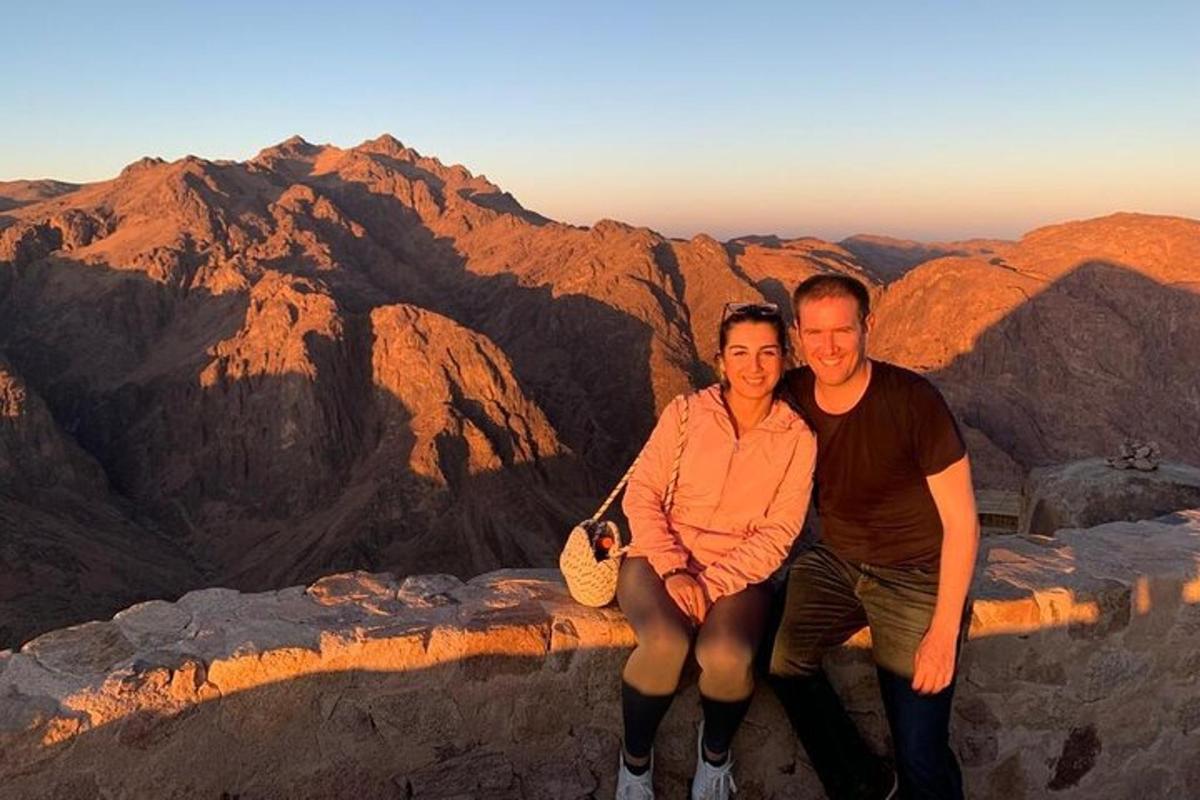un uomo e una donna seduti sul bordo di una montagna