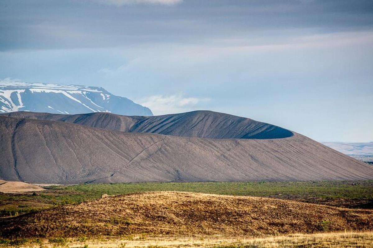 stór brún hæð með snæviþöktu fjalli í bakgrunni