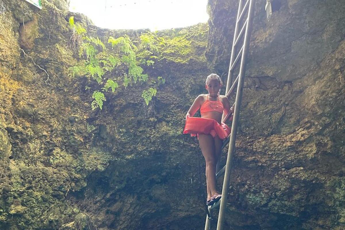 una donna con un vestito arancione in piedi su un ponte di corda