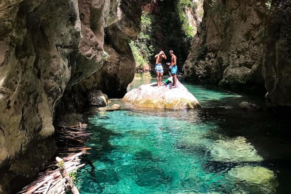 Dos personas de pie sobre una roca en un río.