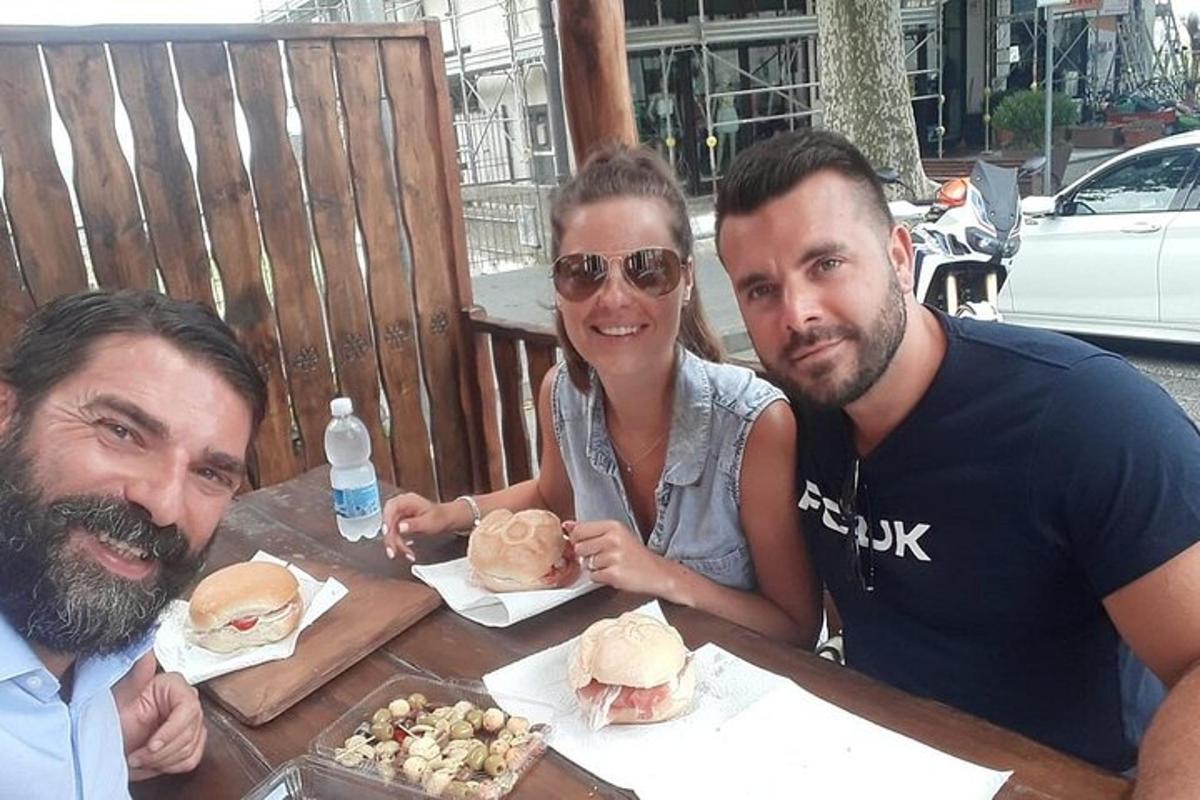 due uomini e una donna seduti a un tavolo con dei panini