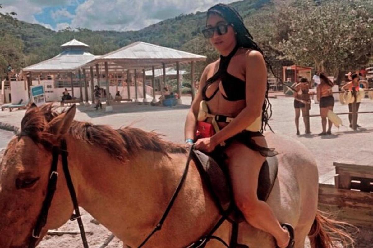 Μια γυναίκα με μπικίνι καβαλάει άλογο στην παραλία