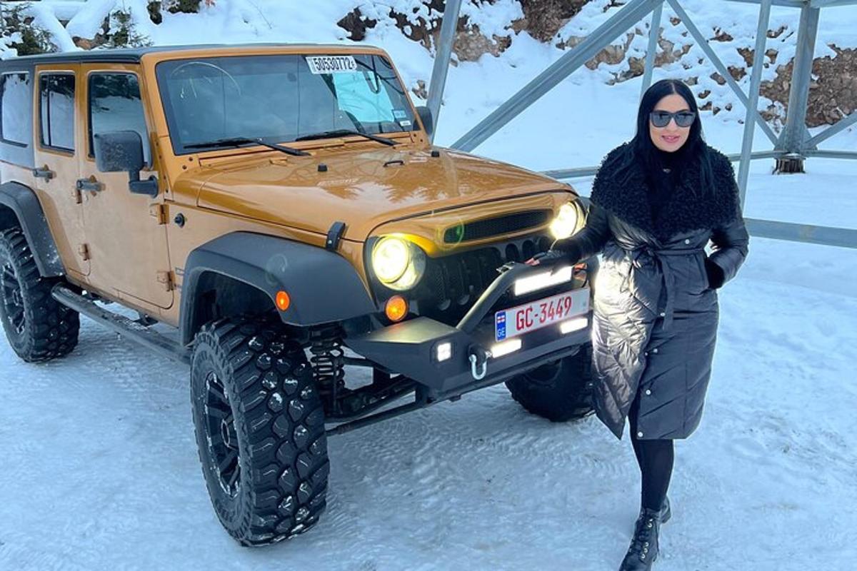 una donna in piedi accanto a una jeep nella neve