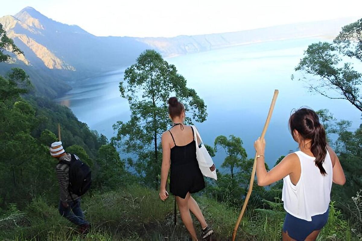 tři lidé stojící na kopci a dívající se na jezero
