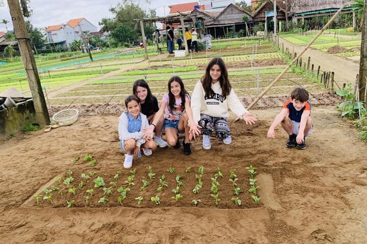 skupina deklet in otrok, ki klečijo okoli vrta
