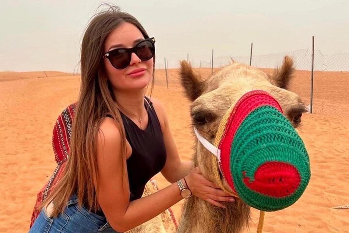 a woman standing next to a camel in the desert