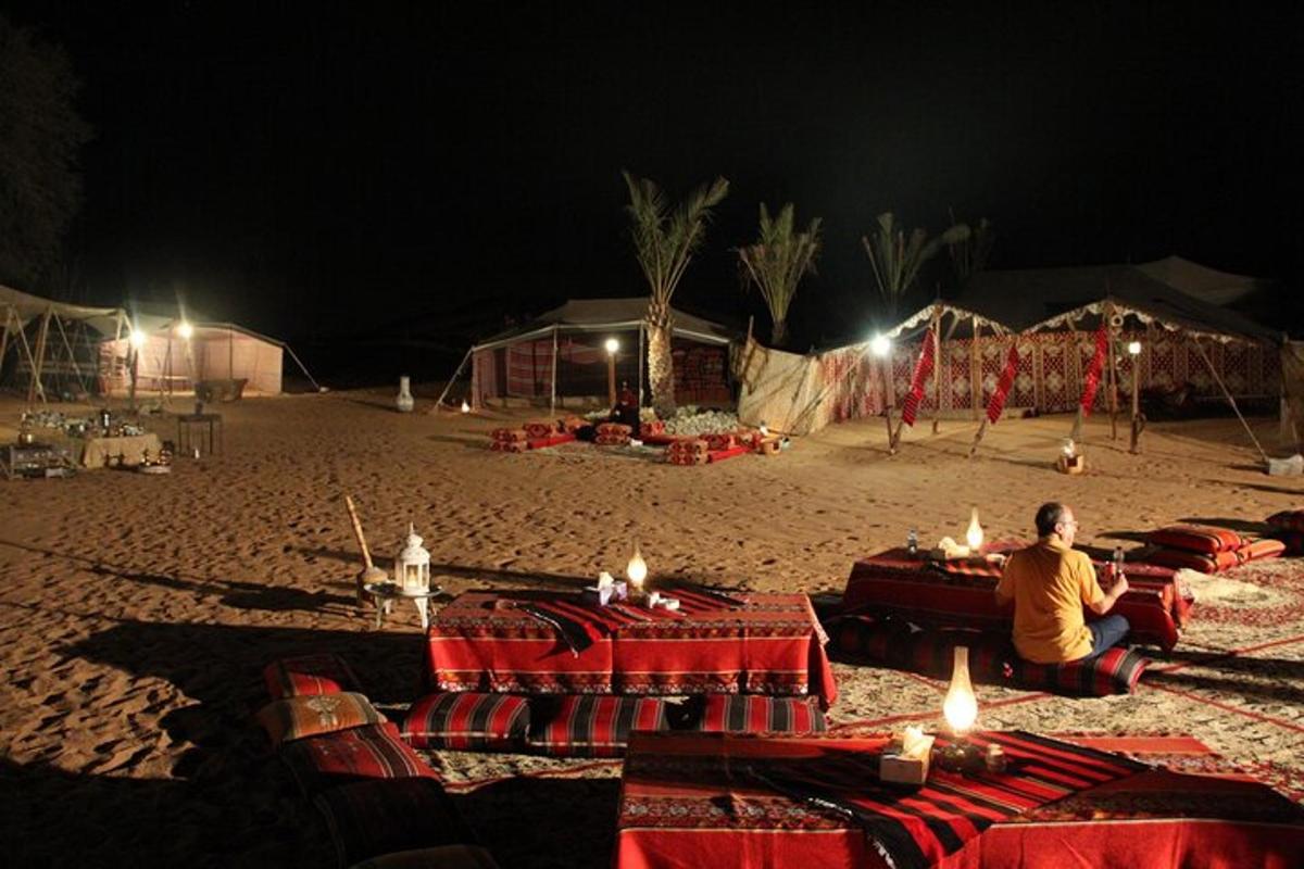 a person sitting on a beach at night with candles on tables