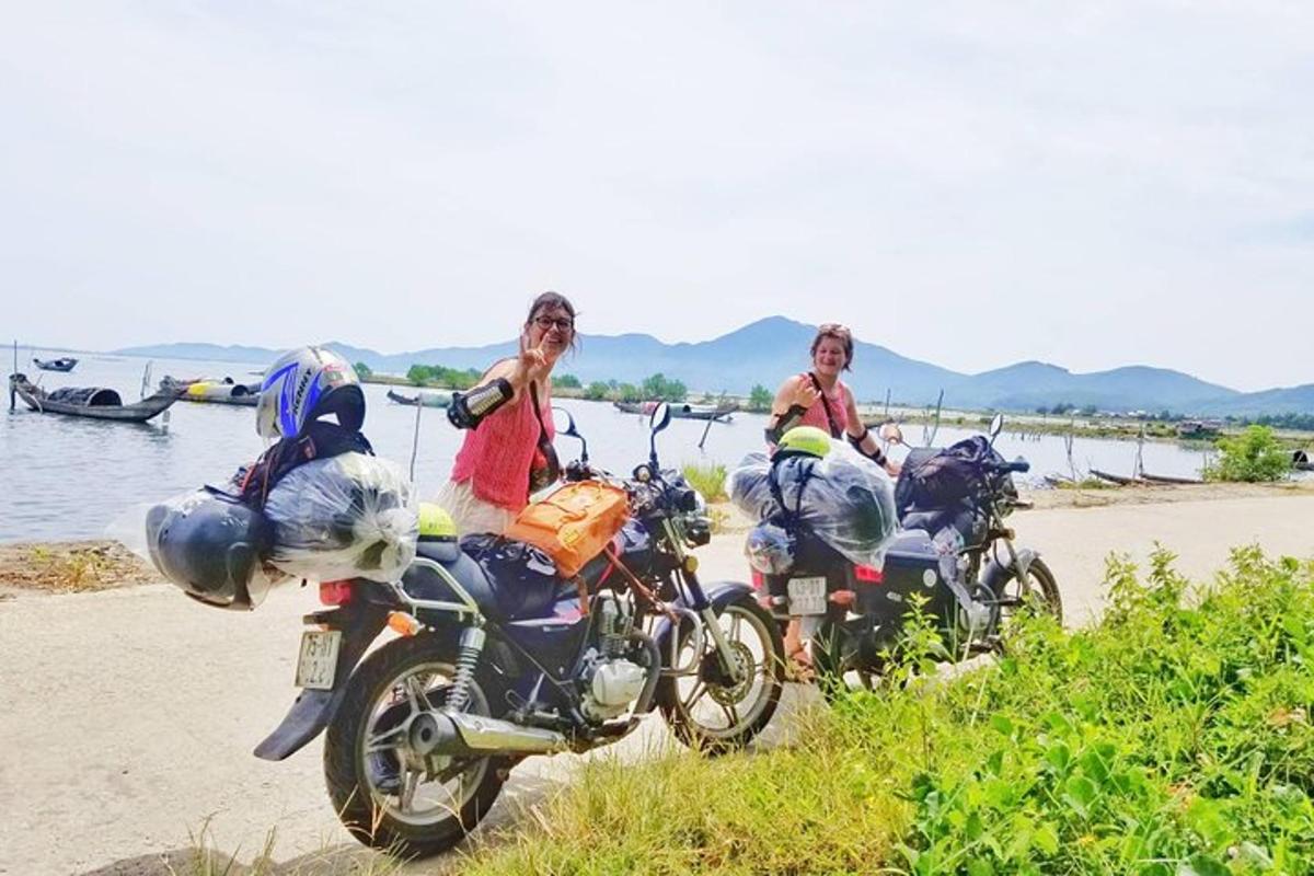 two women are sitting on motorcycles on the beach
