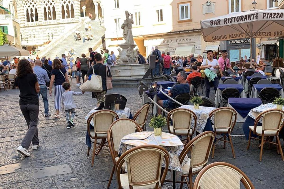 skupina ljudi, ki sedijo za mizami pred fontano