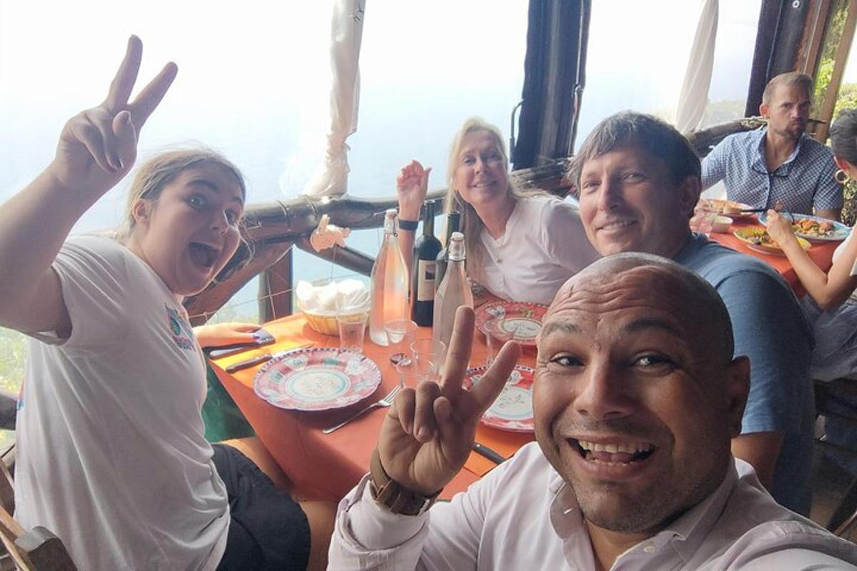 um grupo de pessoas sentadas ao redor de uma mesa fazendo o sinal da paz