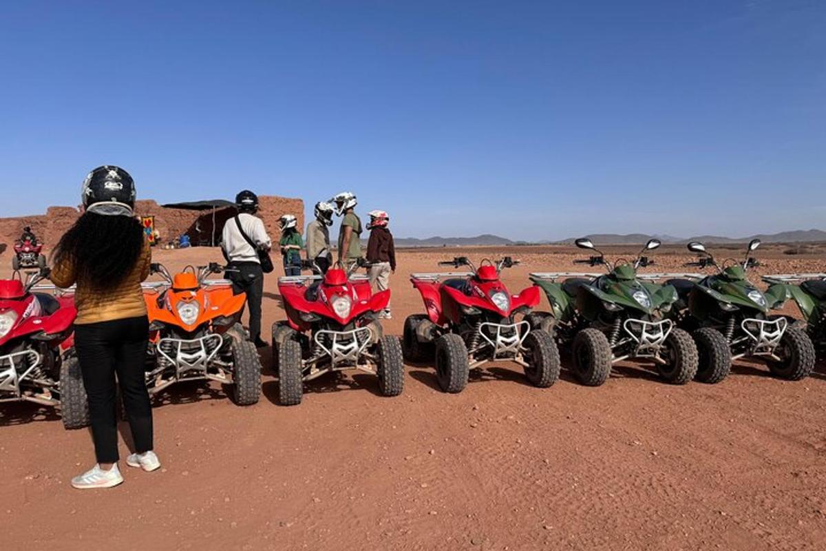 a group of people standing next to four atvs in the desert