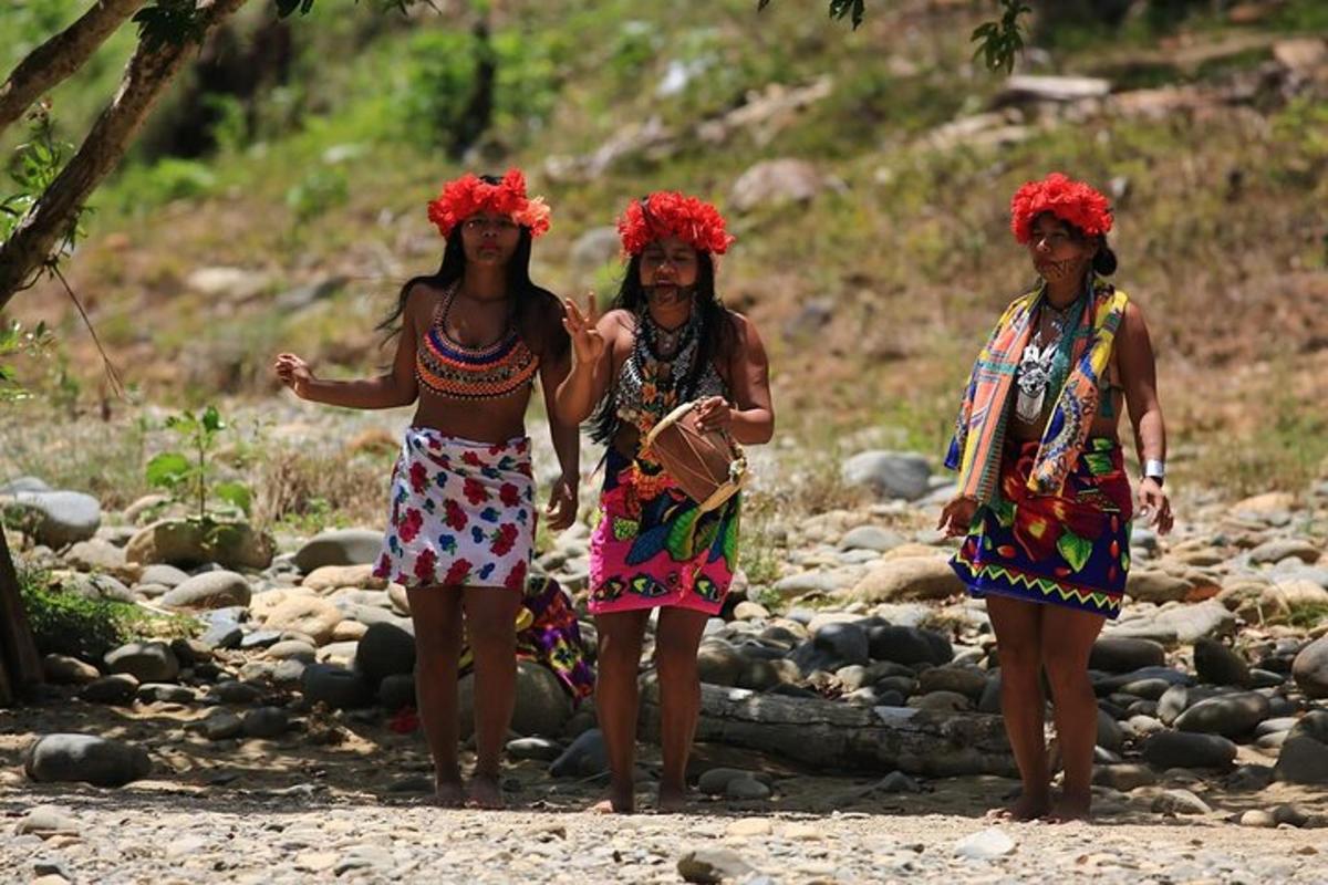 três mulheres em pé sobre rochas com flores vermelhas na cabeça