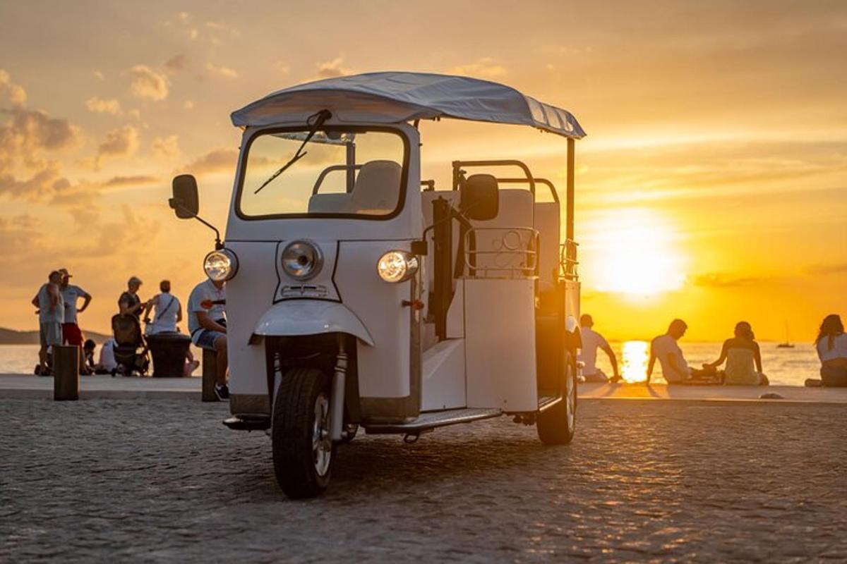 sebuah motor skuter kecil diletakkan di pantai pada waktu matahari terbenam