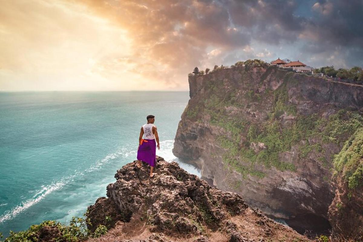 uma mulher em pé em um penhasco com vista para o oceano