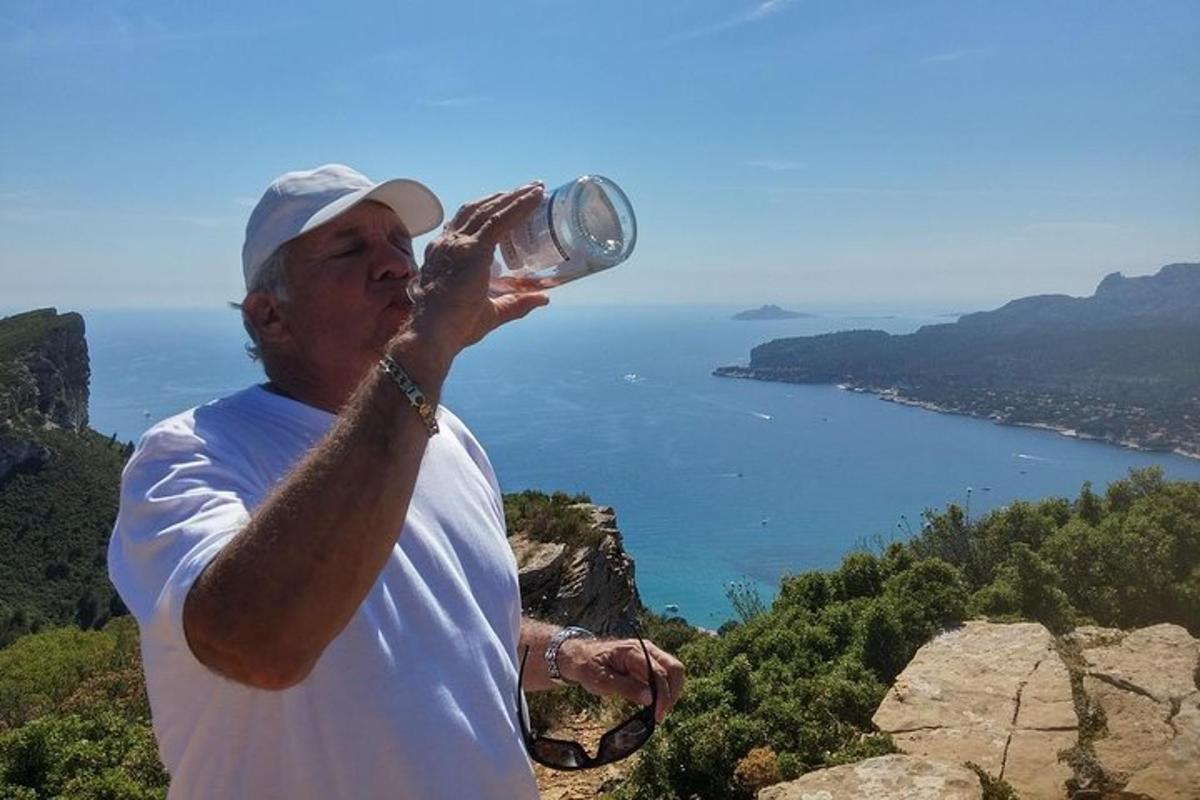 moški, ki pije iz skodelice na vrhu gore