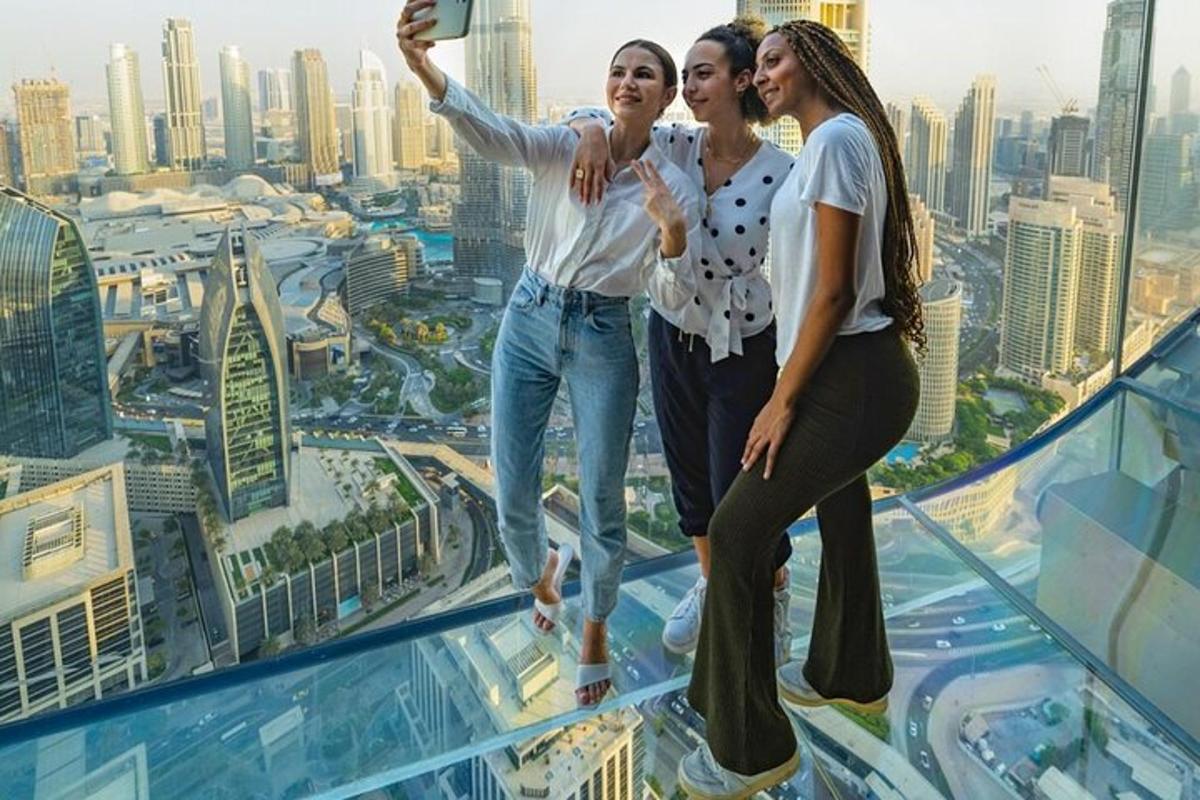 Tres chicas de pie sobre el suelo de cristal de un edificio.