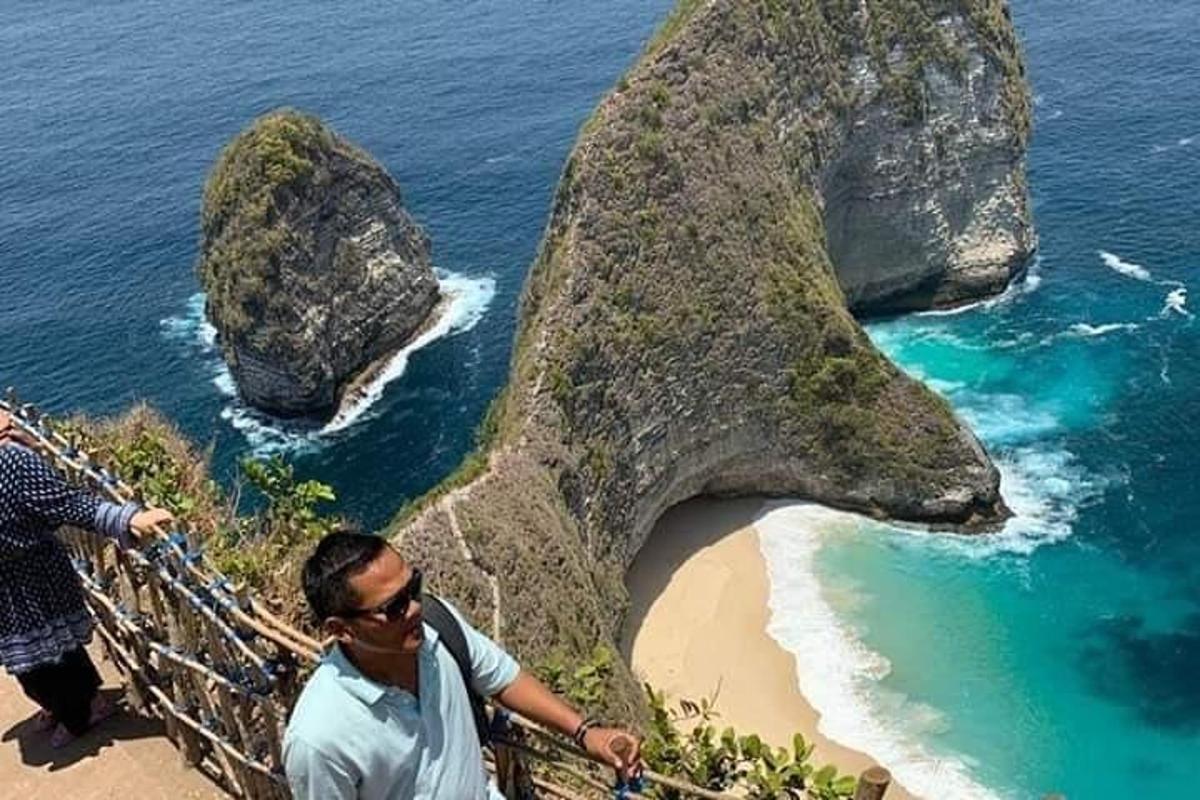 a man standing on top of a cliff next to a beach