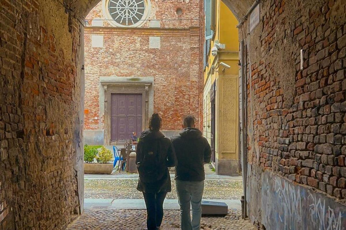dues persones caminant per un carreró amb un rellotge en un edifici
