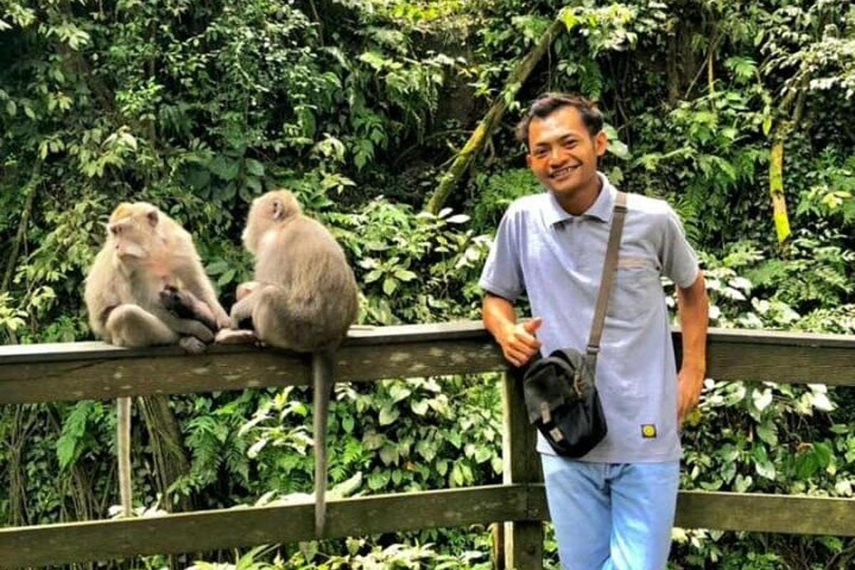 seorang lelaki berdiri di sebelah dua ekor monyet di atas pagar