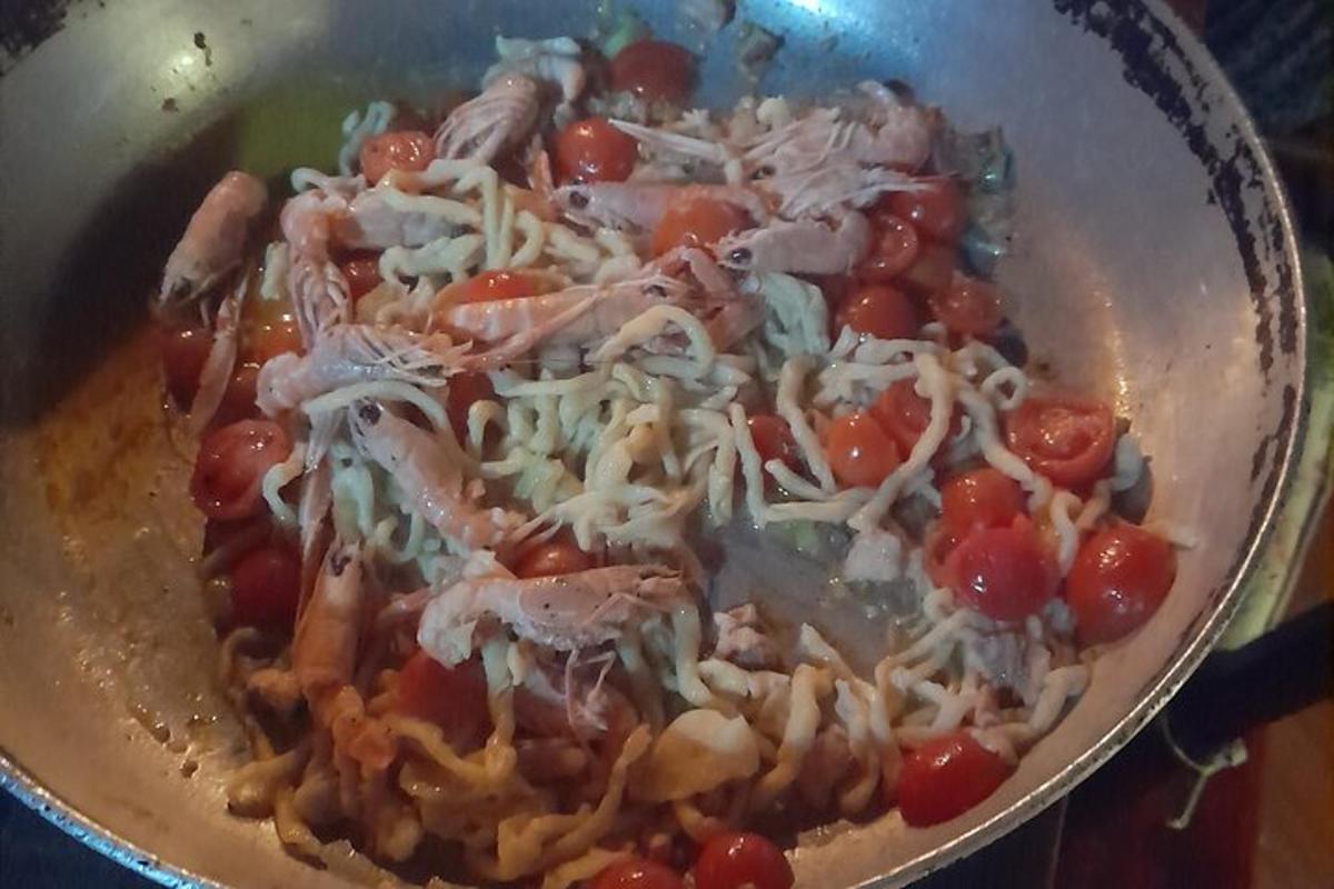 una pentola piena di pasta con pomodori e formaggio