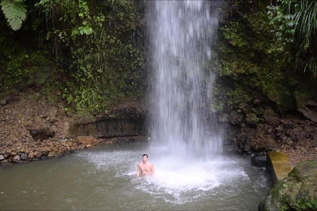 a man in the water in front of a waterfall