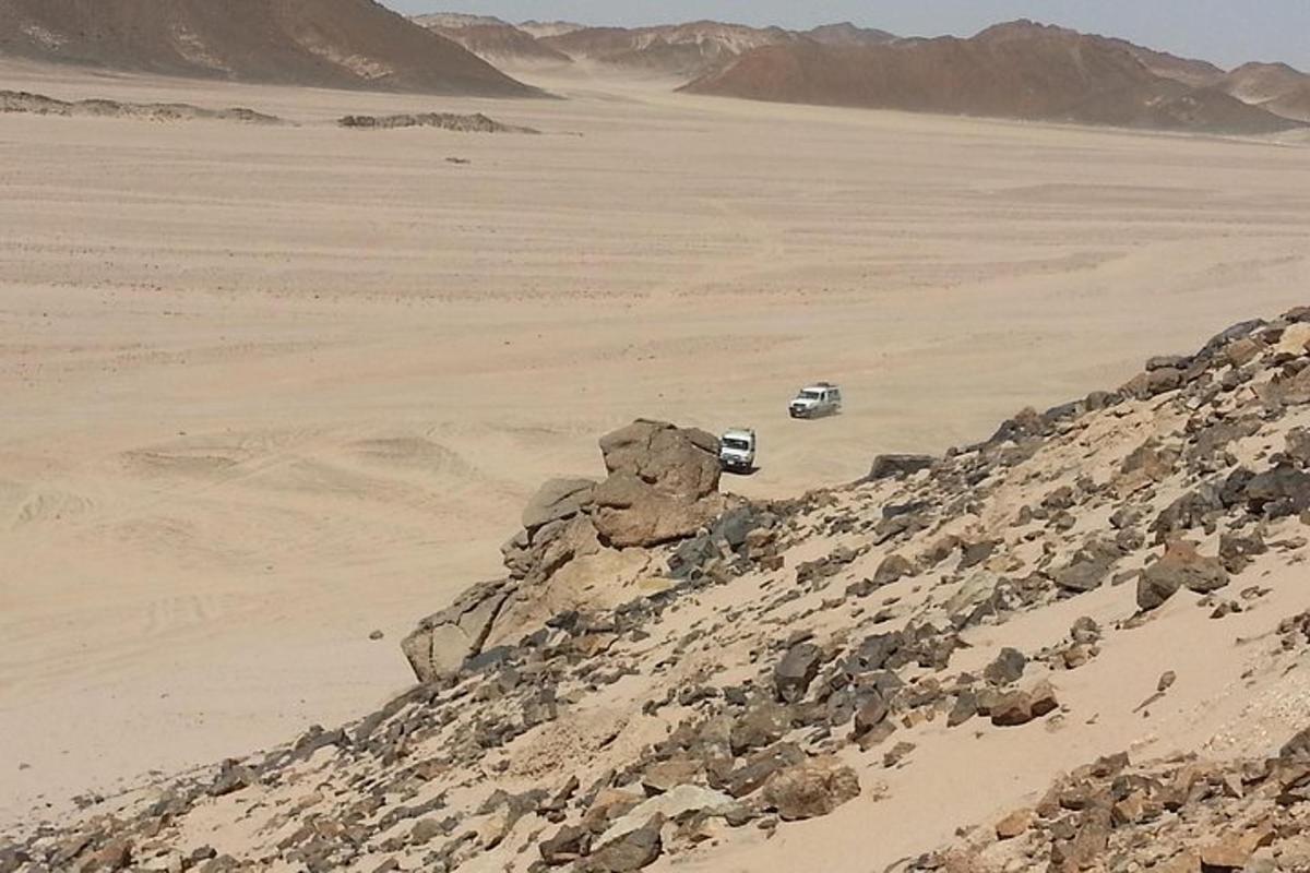 çölde bir kaya yığınının yakınında park edilmiş bir araba