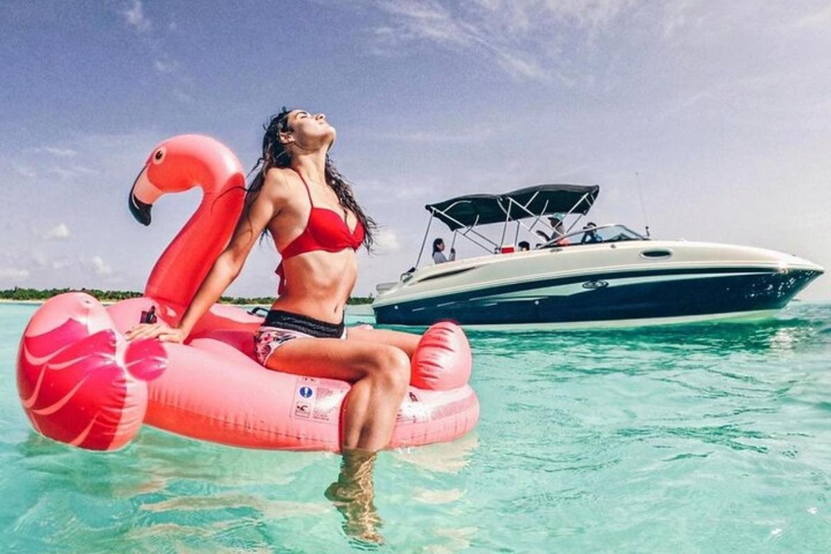 một người phụ nữ mặc bikini ngồi trên bè trên mặt nước với một chiếc thuyền