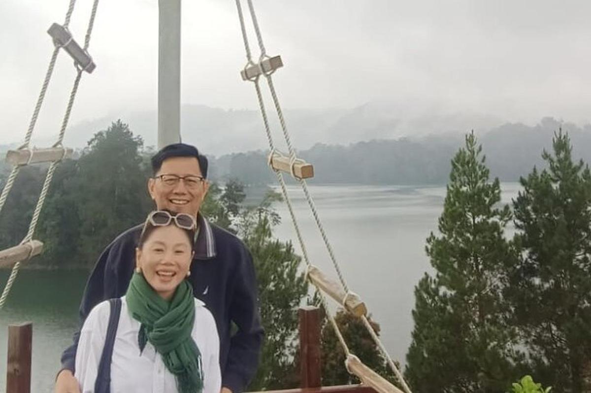 Un hombre y una mujer de pie en un puente colgante sobre un lago.
