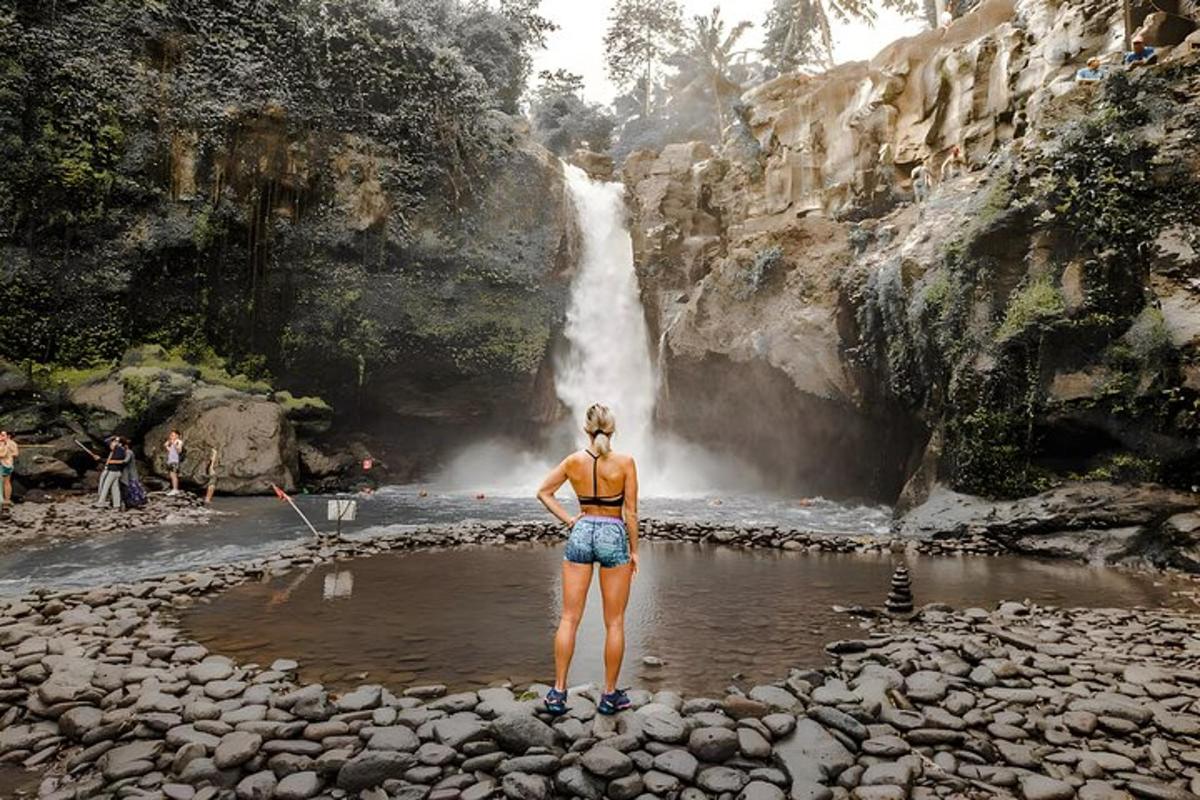 kona stendur fyrir framan foss