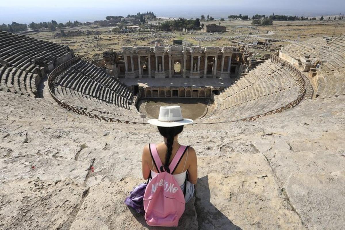 a woman in a hat sitting in an amphitheatre
