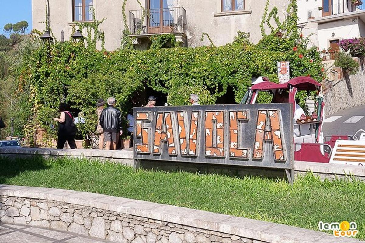 un semn de lemn pe care scrie „arma” în fața unei clădiri