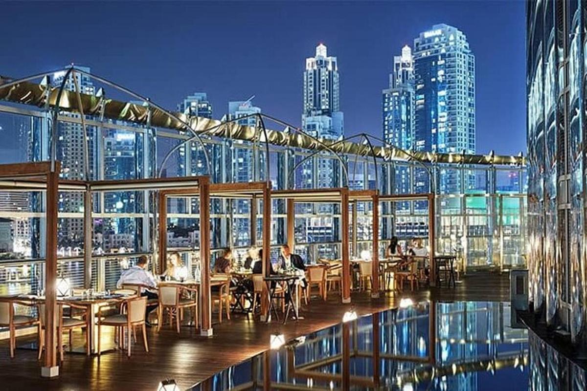 bir binanın üzerinde masalarda oturan insanların olduğu bir restoran