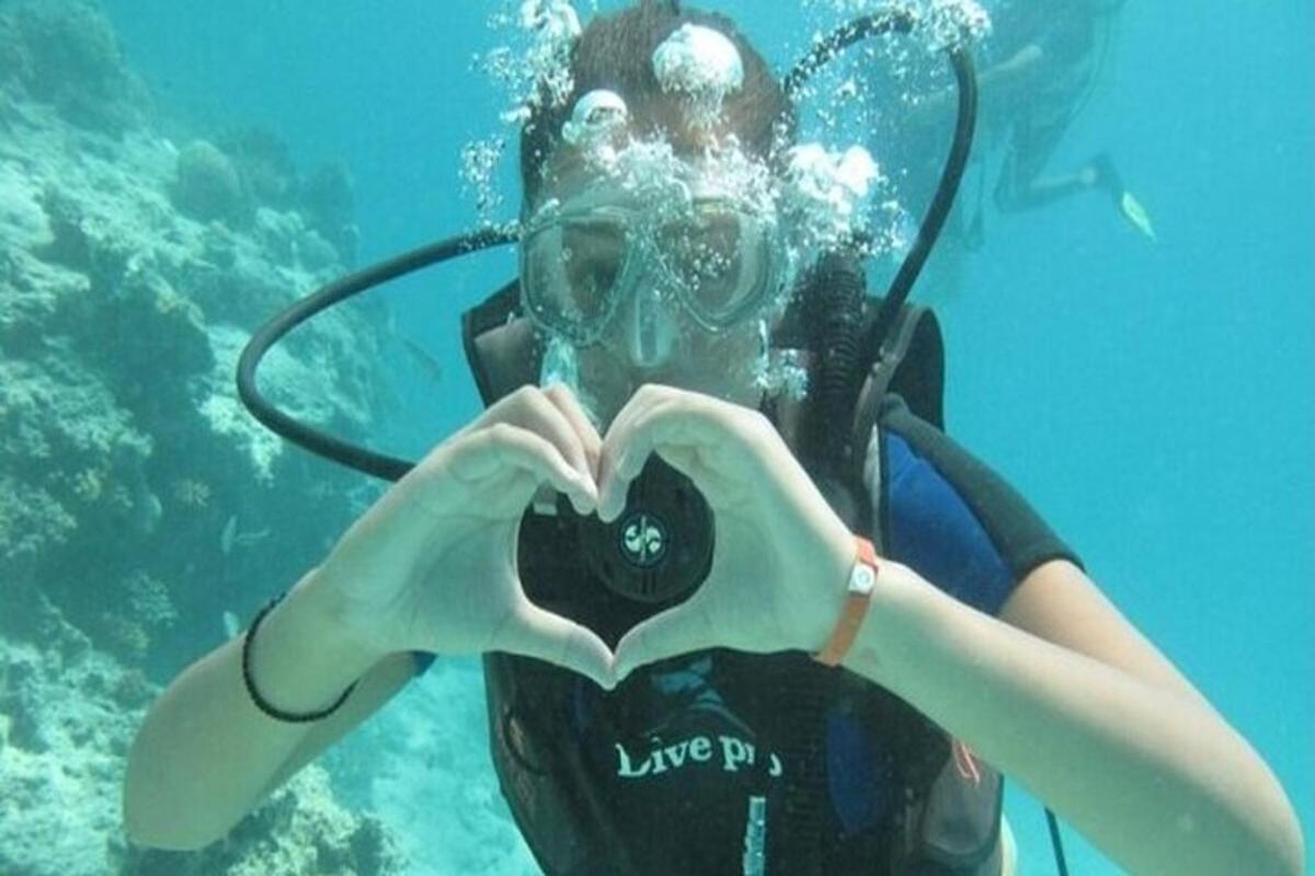 ผู้หญิงกำลังทำรูปหัวใจโดยใช้กล้องในน้ำ