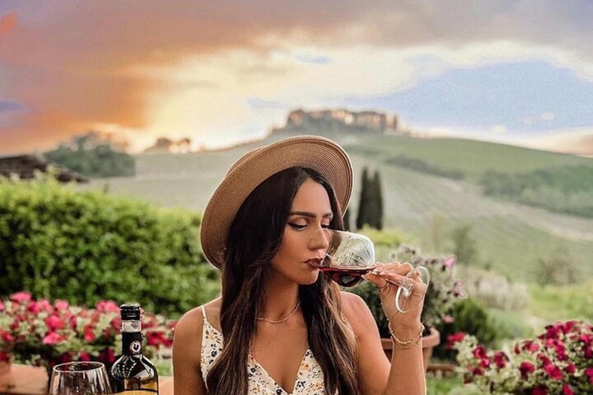 žena sedící u stolu a pije sklenici vína