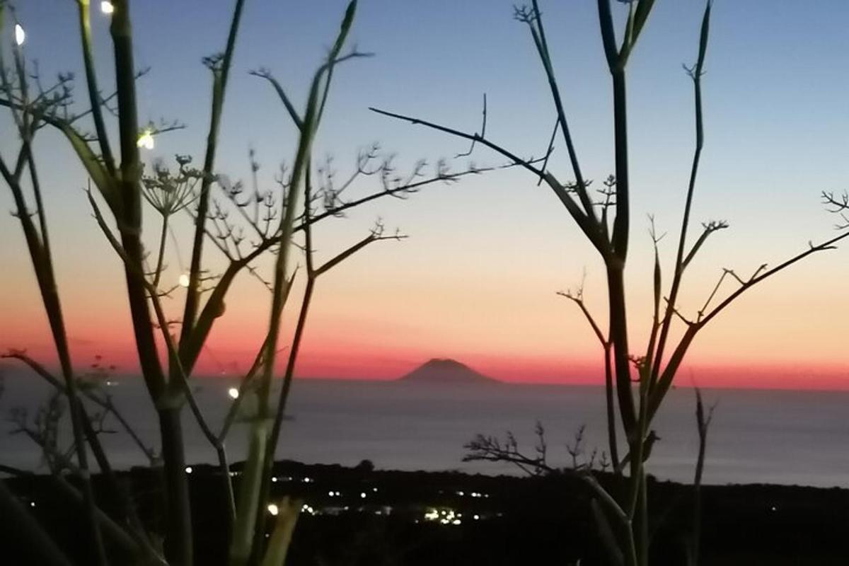 a sunset over the ocean with a mountain in the distance