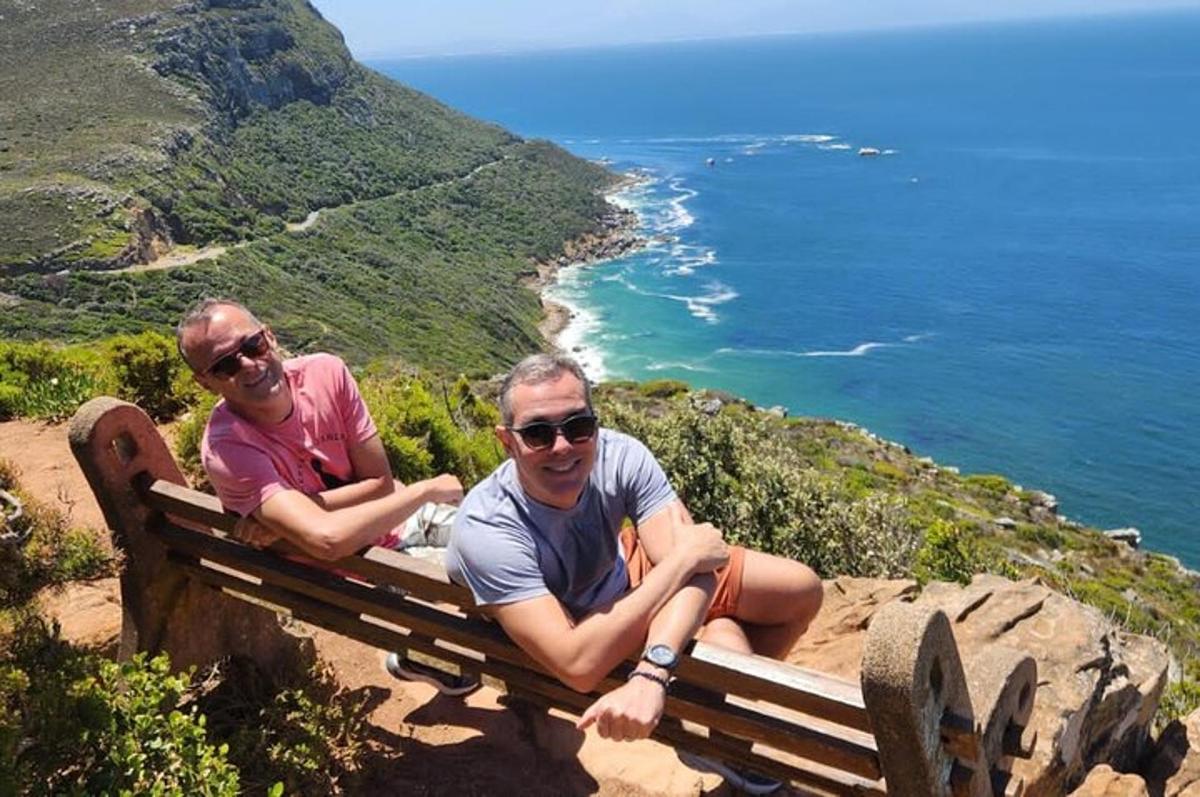doi bărbați așezați pe o bancă cu vedere la ocean