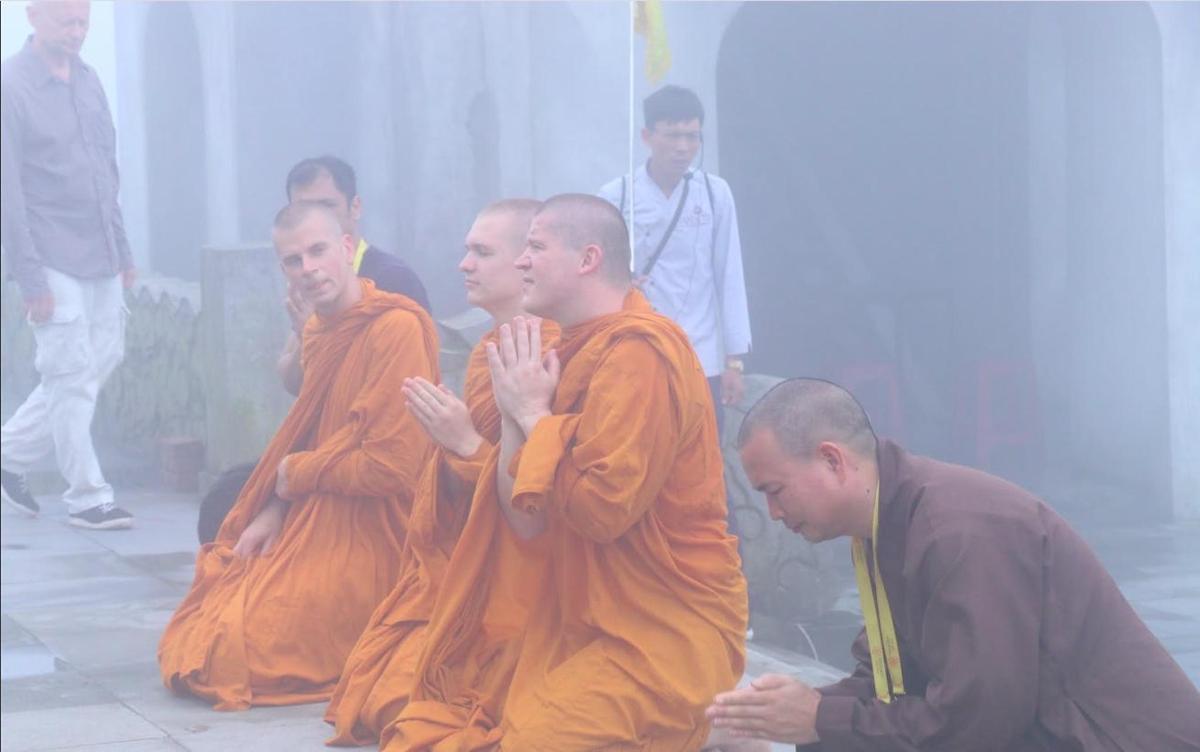 a group of monks in orange robes praying