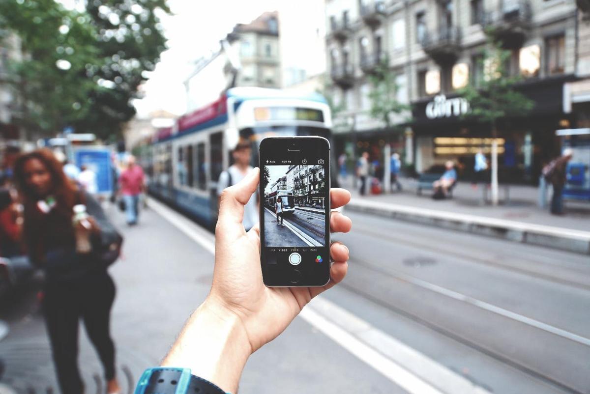eine Person, die mit einem Mobiltelefon ein Foto von einer Straße macht