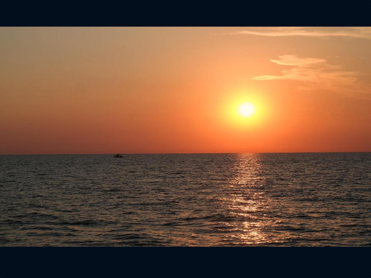 an orange sunset over the ocean with a boat