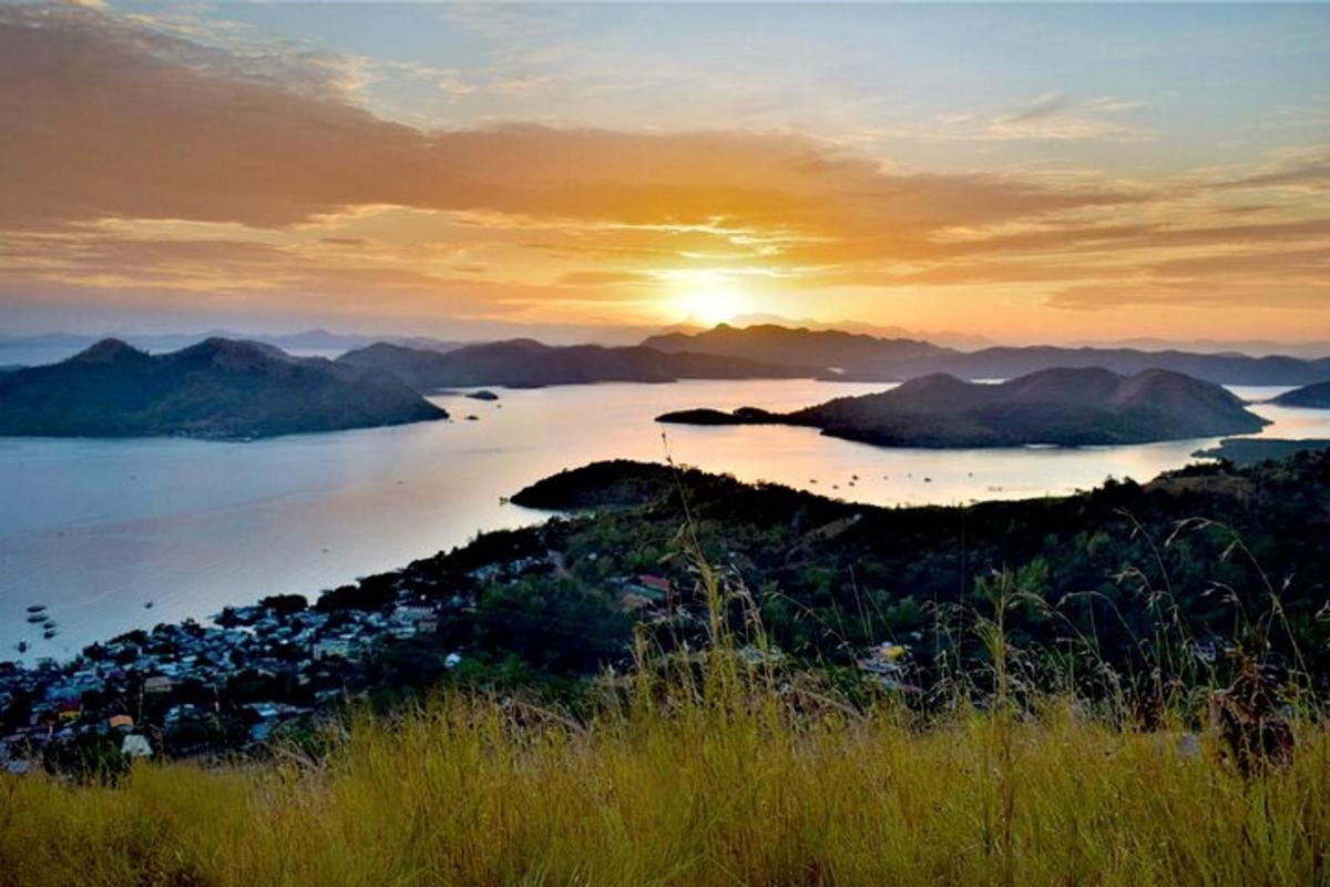 a sunset over a body of water with mountains