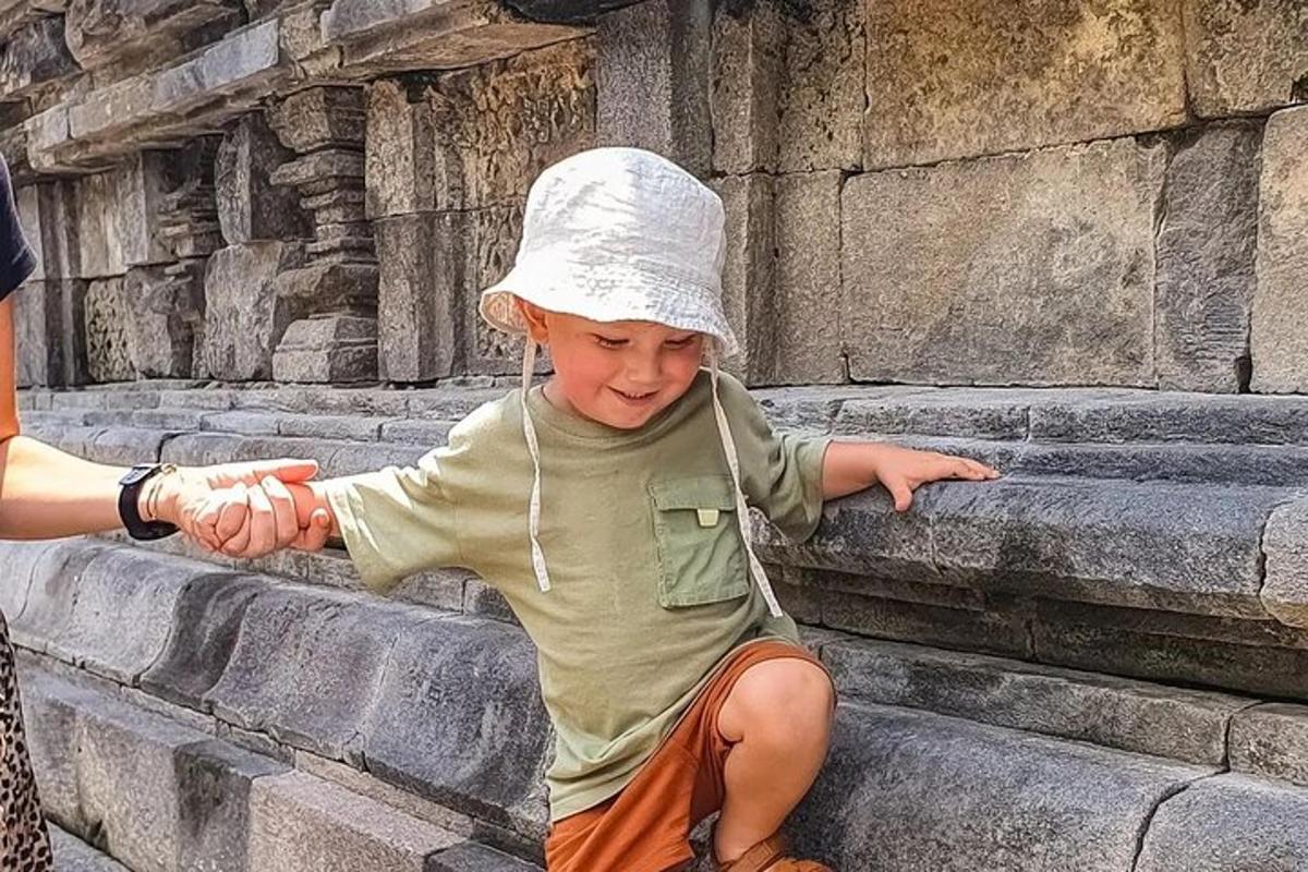 một cậu bé đang ngồi trên bậc đá