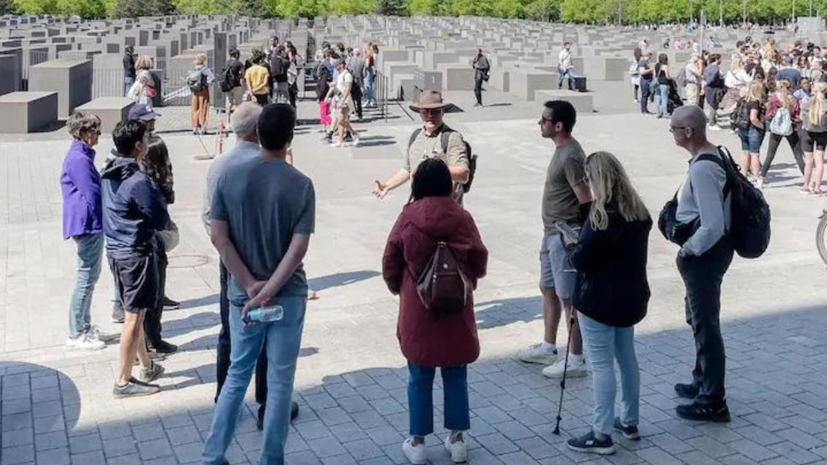 μια ομάδα ανθρώπων που στέκονται τριγύρω σε ένα νεκροταφείο