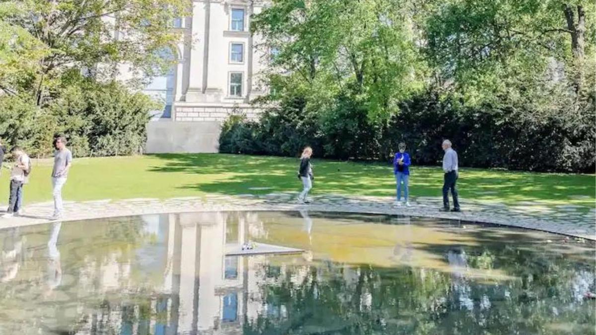um grupo de pessoas em pé ao redor de um lago em um parque