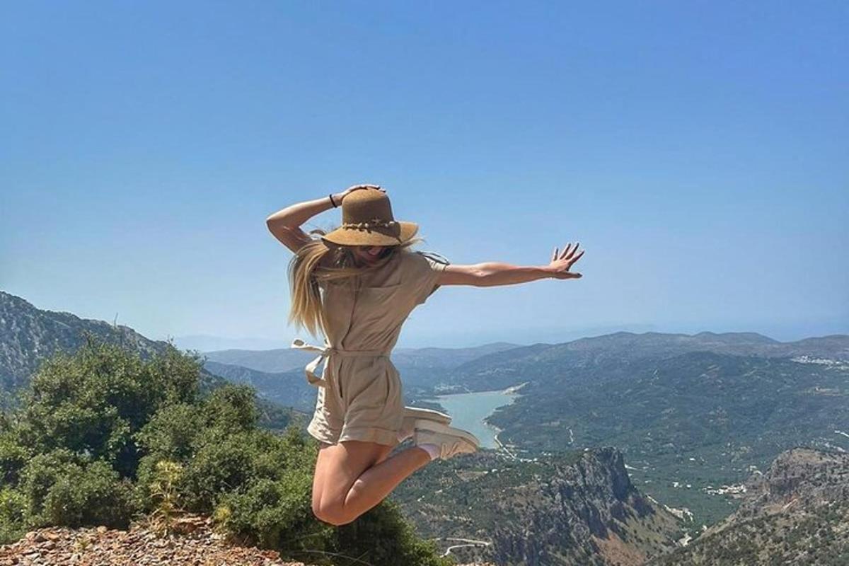 uma mulher pulando no ar no topo de uma montanha