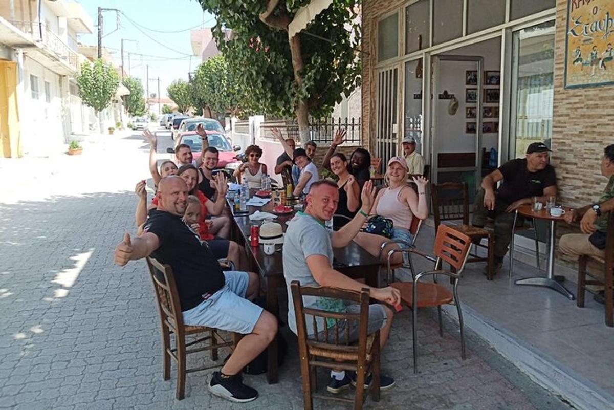 μια ομάδα ανθρώπων που κάθονται σε τραπέζια έξω από ένα εστιατόριο