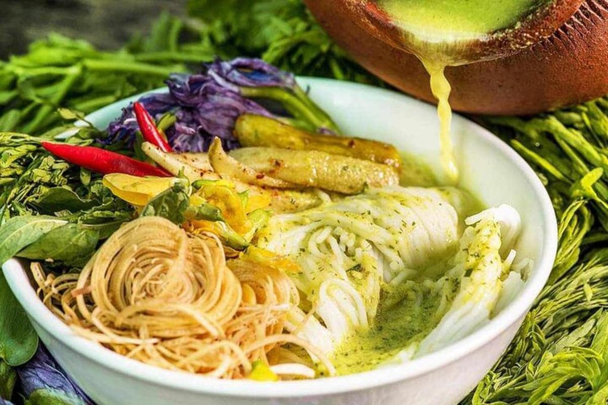 một bát thức ăn màu trắng với mì và rau