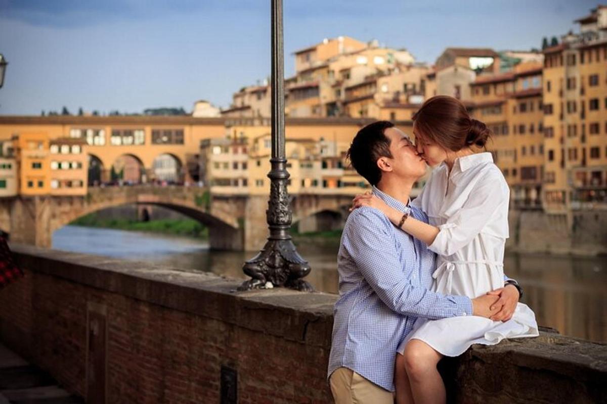 Un hombre y una mujer sentados en un puente besándose