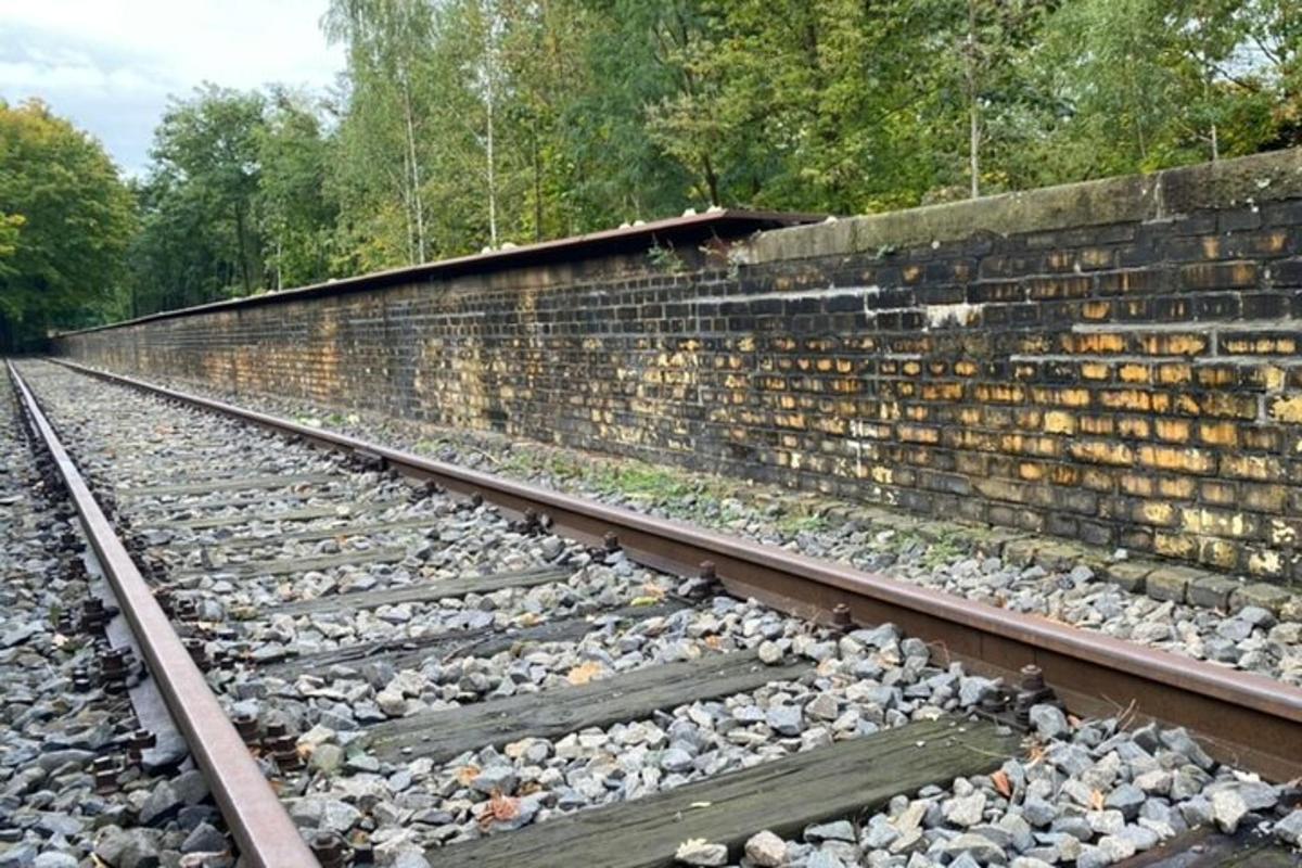 un binario ferroviario vuoto accanto a un muro di mattoni
