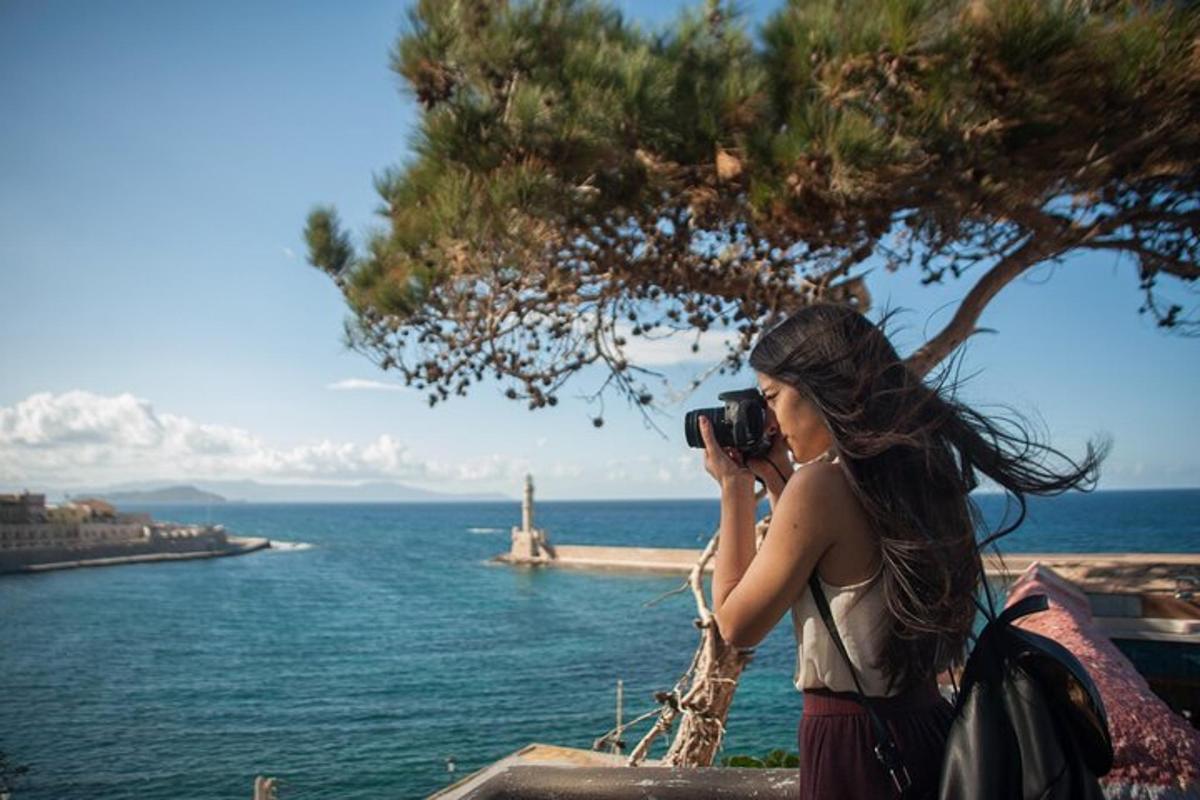 ženska, ki s fotoaparatom fotografira ocean