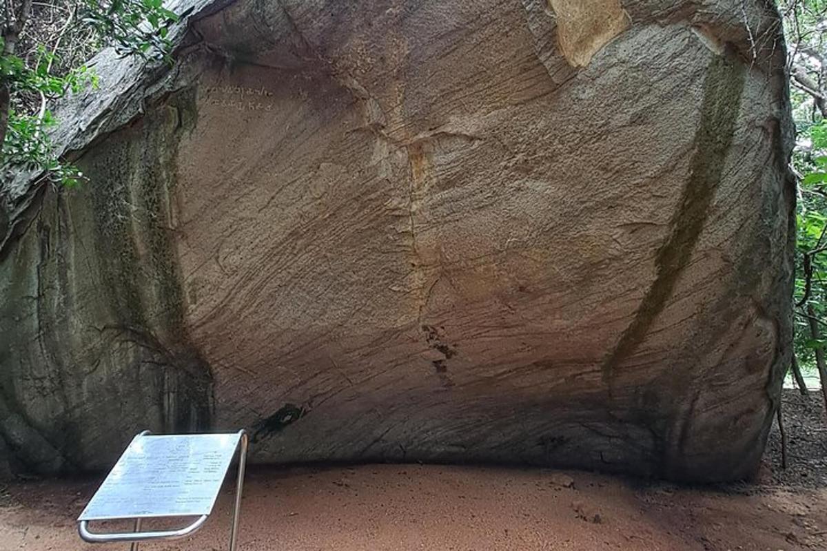 a sign in front of a large rock